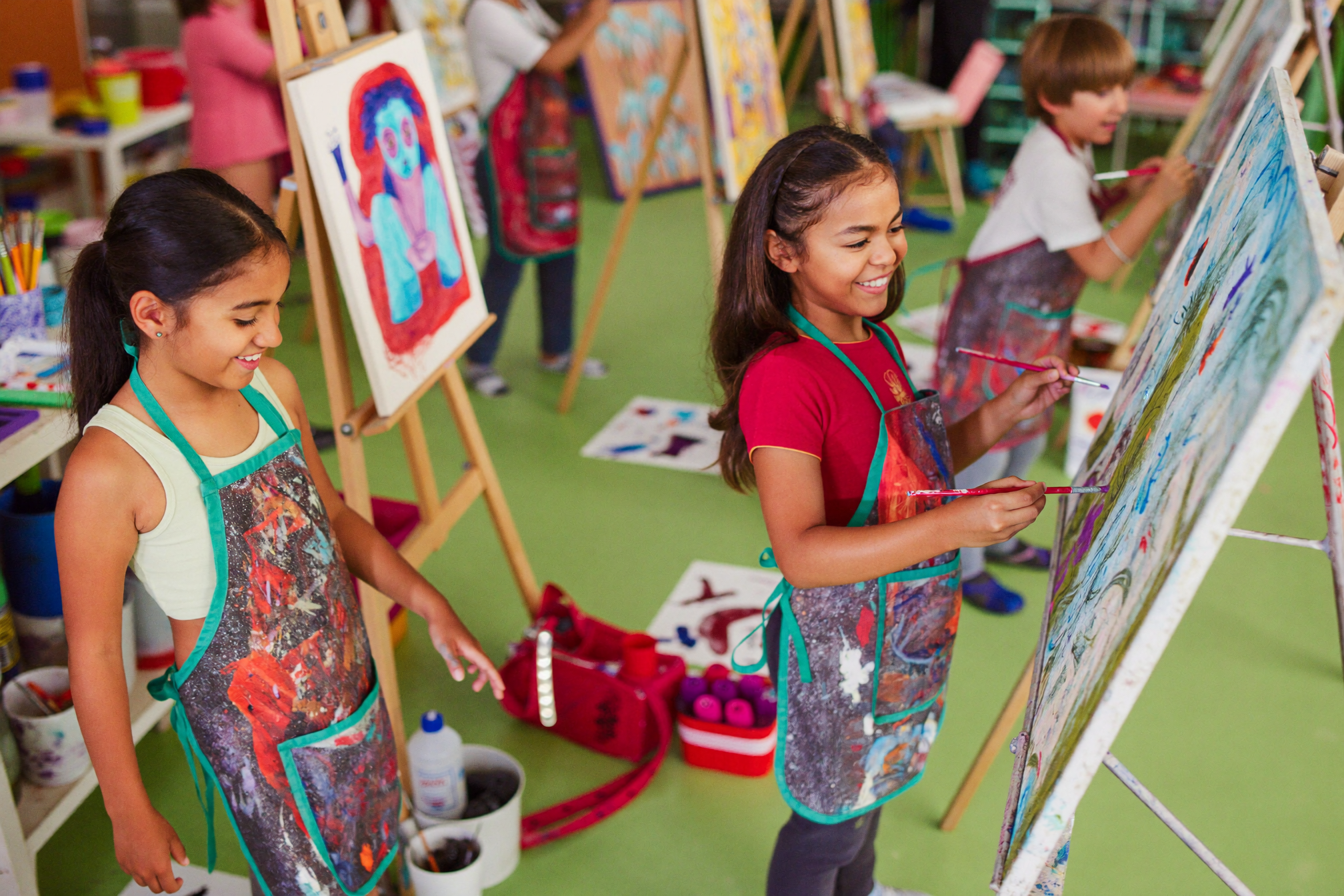 Children painting at easels in a bright art studio